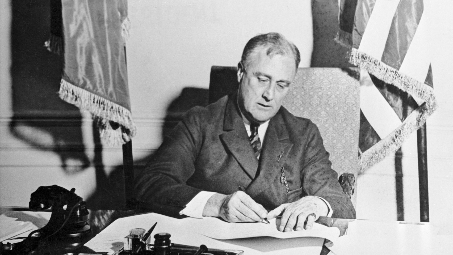 Franklin D Roosevelt signing the emergency banking act in 1933