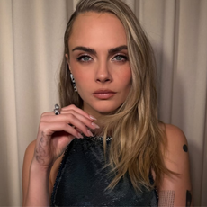 Image of Cara Delevingne showing of her manicure, wearing hand cream. 