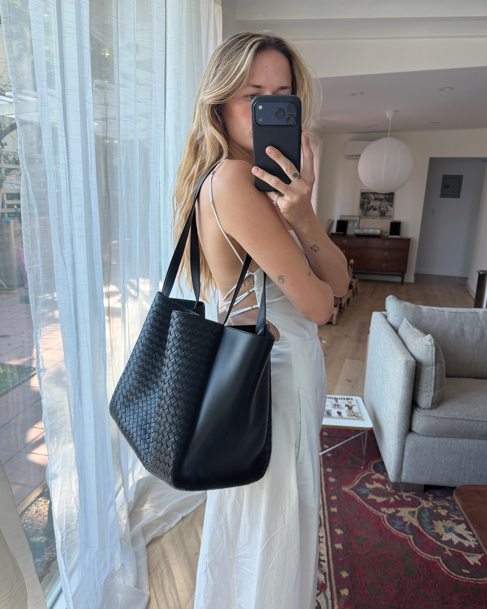 Eliza Huber wearing a white dress, sandals, and the new Bottega Veneta Corso bag.