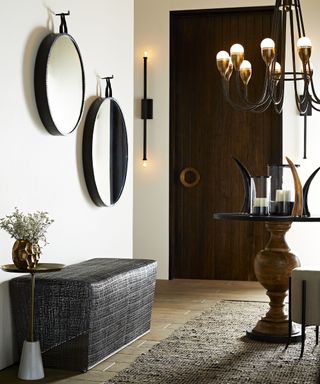 Modern entryway bench ideas with a black woven bench, black circular mirrors and black pendant light feature