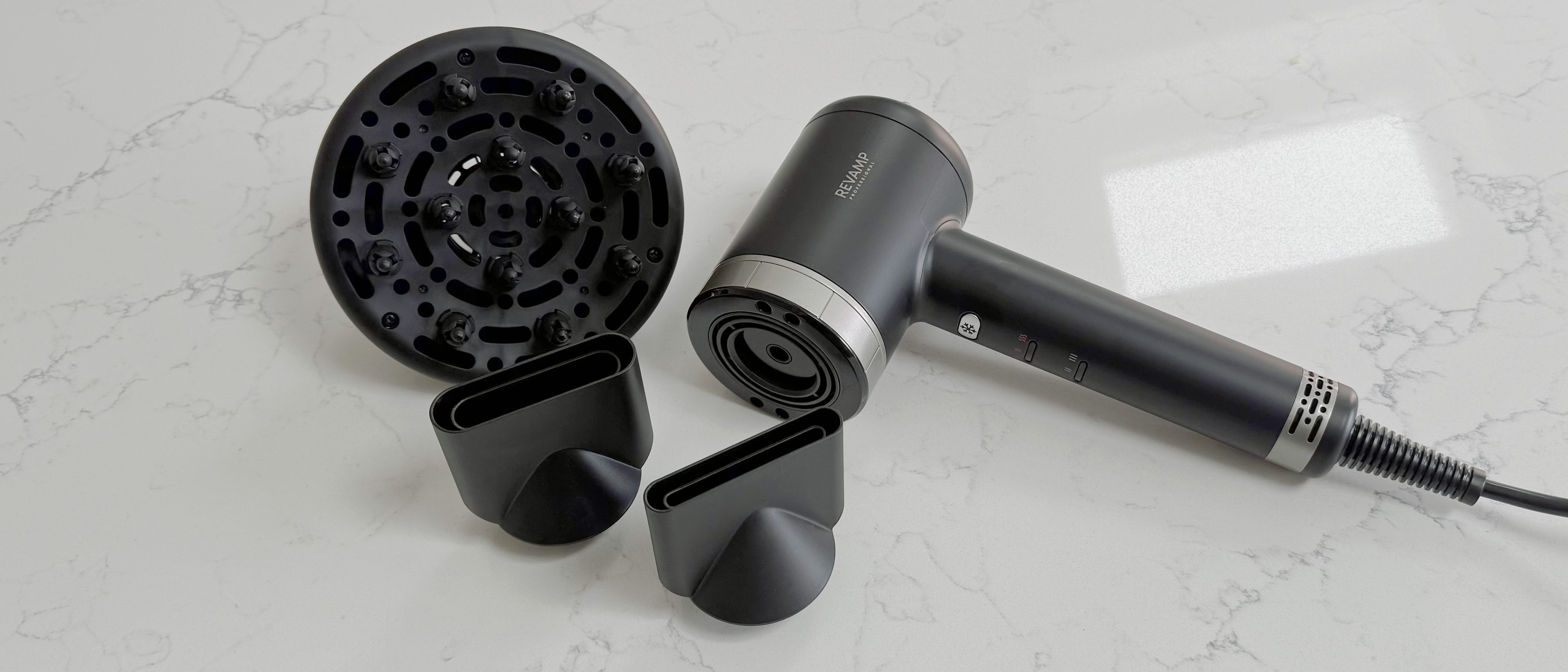 Wide shot of the Revamp Tri-Care hair dryer laid out with its diffuser and nozzle attachments on a countertop