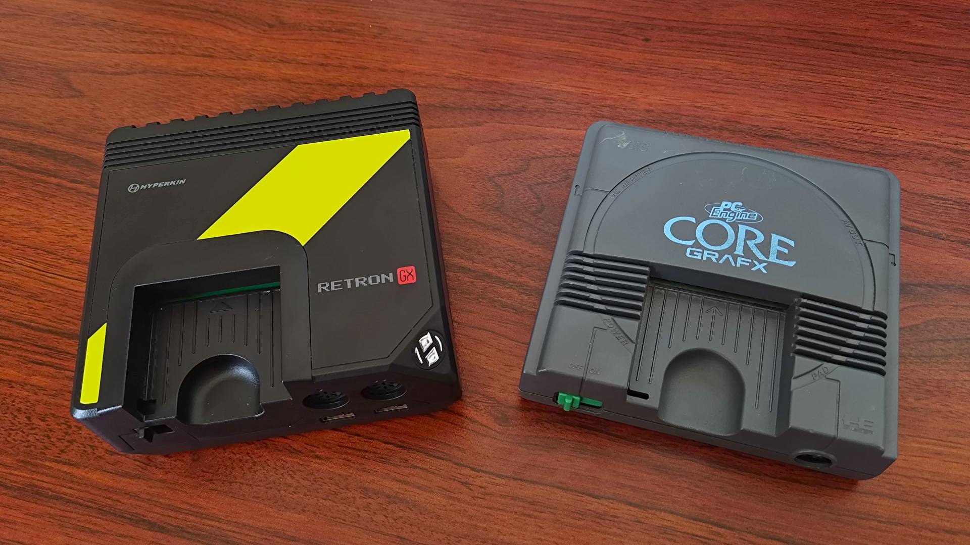 Hyperkin Retron GX next to original PC Engine on woodgrain desk.