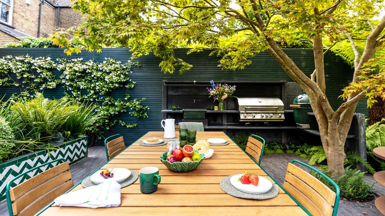 garden makeover with a dining table and chairs, outdoor kitchen with two barbecues and a kitchen sink and patterned tiles