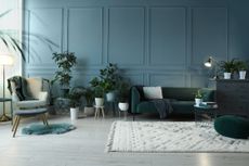 A living room filled with plants features a light blue, grey, and green color scheme.