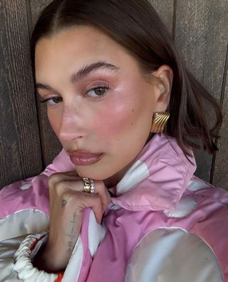 Hailey Bieber wearing shimmery pink blush on her eyes and cheeks.