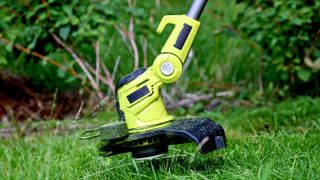 Close up of green cordless strimmer head cutting grass