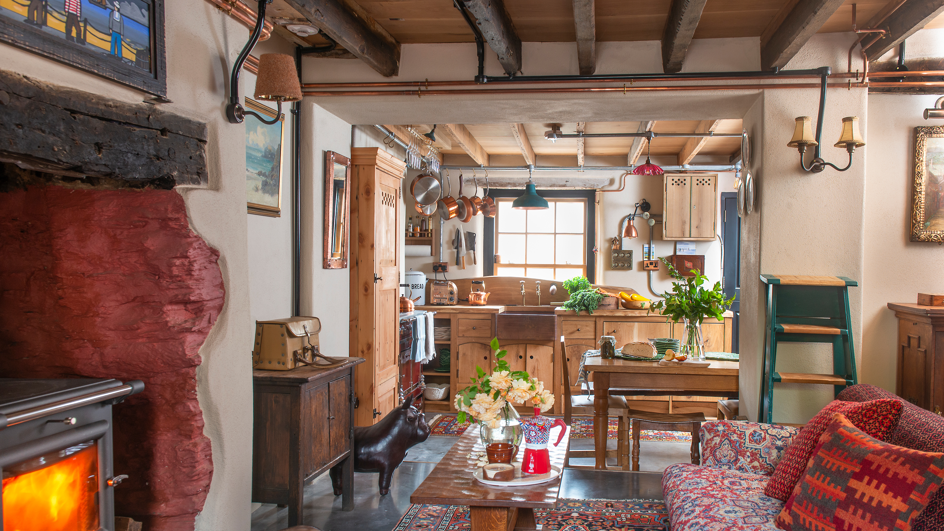 view from living room through to wooden kitchen in a rustic cottage furnished with antiques