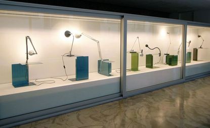 Museum store, Berlin interior room, brown marble floor, white frame display units with spotlights, shining on a variety of desk lamps