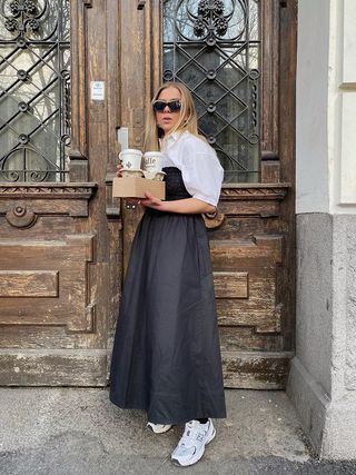 Dina Hansen wearing a black and white dress with New Balance sneakers and sunglasses.