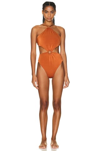 a model wears an orange one-piece swimsuit with a cutout at the waist