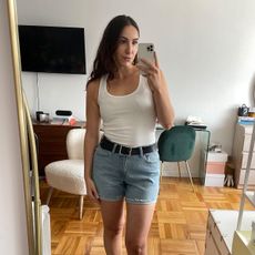 Anna LaPlaca wearing denim shorts, a black belt, and a white tank top.