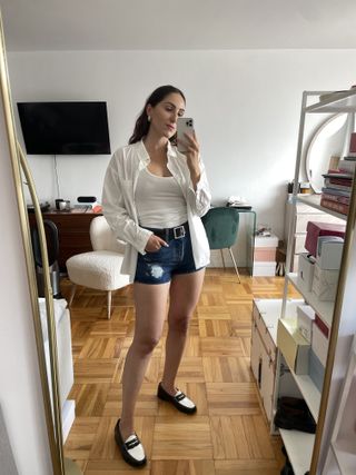 Anna LaPlaca wearing Levi's 501 Original Shorts, a white tank top, white button-down shirt, a black belt, and loafers.