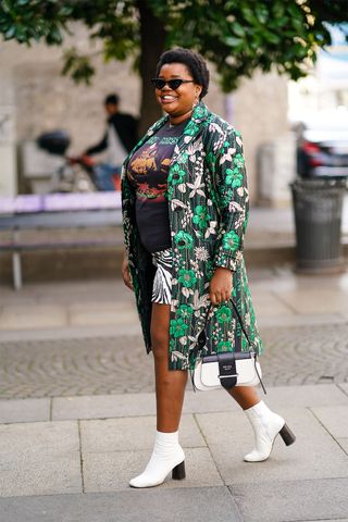 Woman wearing a long coat with a T-shirt, a miniskirt, and ankle boots.