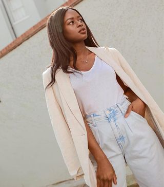 a woman wears a cream blazer with a white T-shirt tucked into jeans