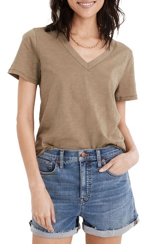 a model wears a light brown V-neck T-shirt with denim shorts