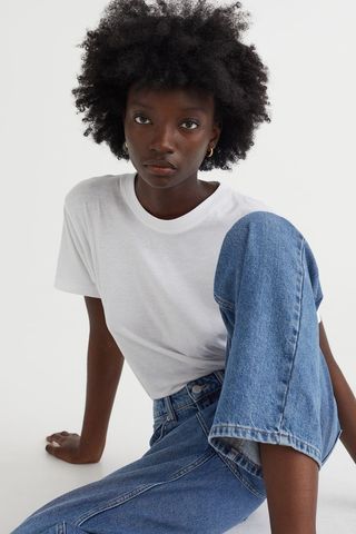a model wears a white creneck T-shirt with jeans