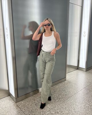 @elizagracehuber wearing white tank, green cargo pants, and black mules