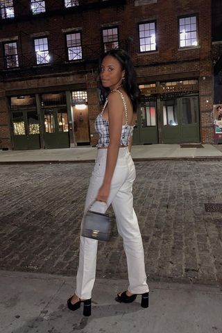 outfits to wear on a first date shown on a woman wearing statement top with white jeans and black platform heels and handbag