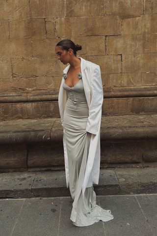 a photo showing black tie attire for women with a woman wearing a gray gown with a white coat