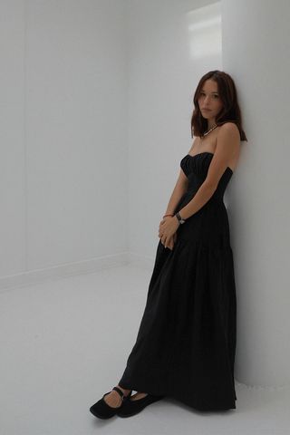 a photo of a woman's outfit with ballet mary jane flats a black maxi dress