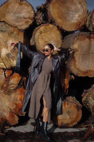 a photo of a woman's outfit with flat black combat boots and a tan knit wrap dress and a black leather trench coat