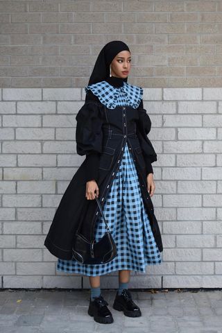 a woman's outfit with flat black oxfords and a plaid print dress layered under a denim dress