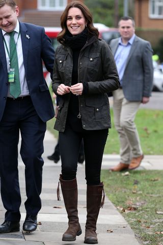 best riding boots shown in a photo of Kate Middleton wearing a green barn jacket over a black turtleneck with black skinny jeans and brown knee-high riding boots