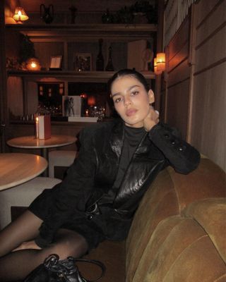 A woman wears a leather blazer and a black minidress.