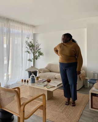 Abi wears a brown turtleneck sweater, blue pants, and black flip-flops.