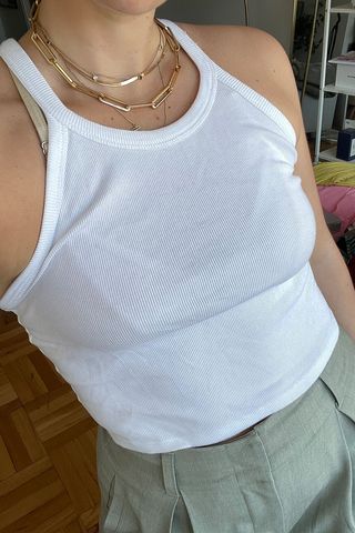 close up shot of Anna LaPlaca wearing white tank top and green trousers