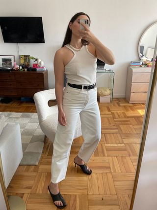 Anna LaPlaca wearing white tank top, white jeans, and black sandals