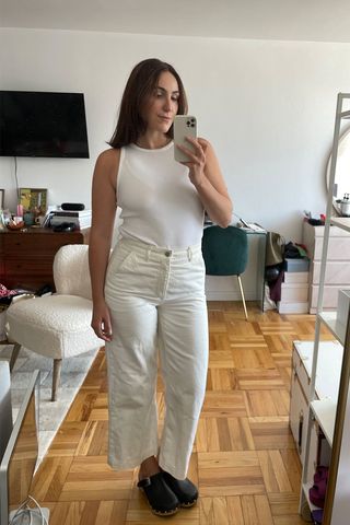 Anna LaPlaca wearing white tank top, white jeans, and clogs