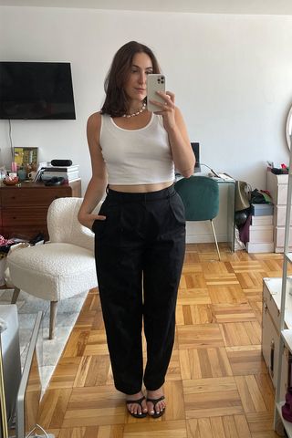 Anna LaPlaca wearing cropped white tank top and fitted trousers