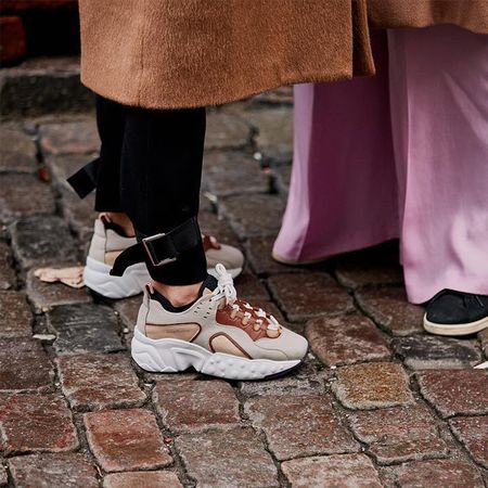 Woman wearing black pants with chunky sneakers.