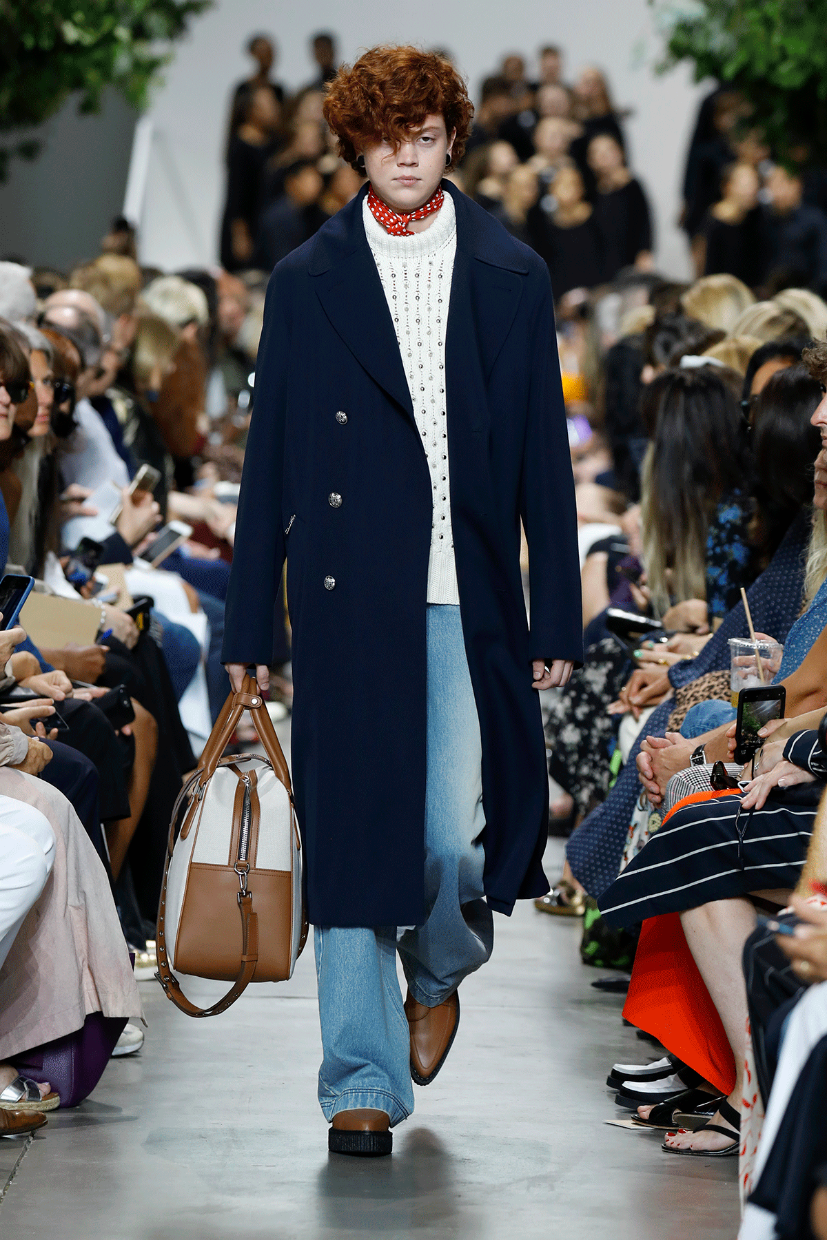 a photo showing how to style straight-leg jeans with a model wearing a navy coat over a white sweater with straight jeans and cowboy boots