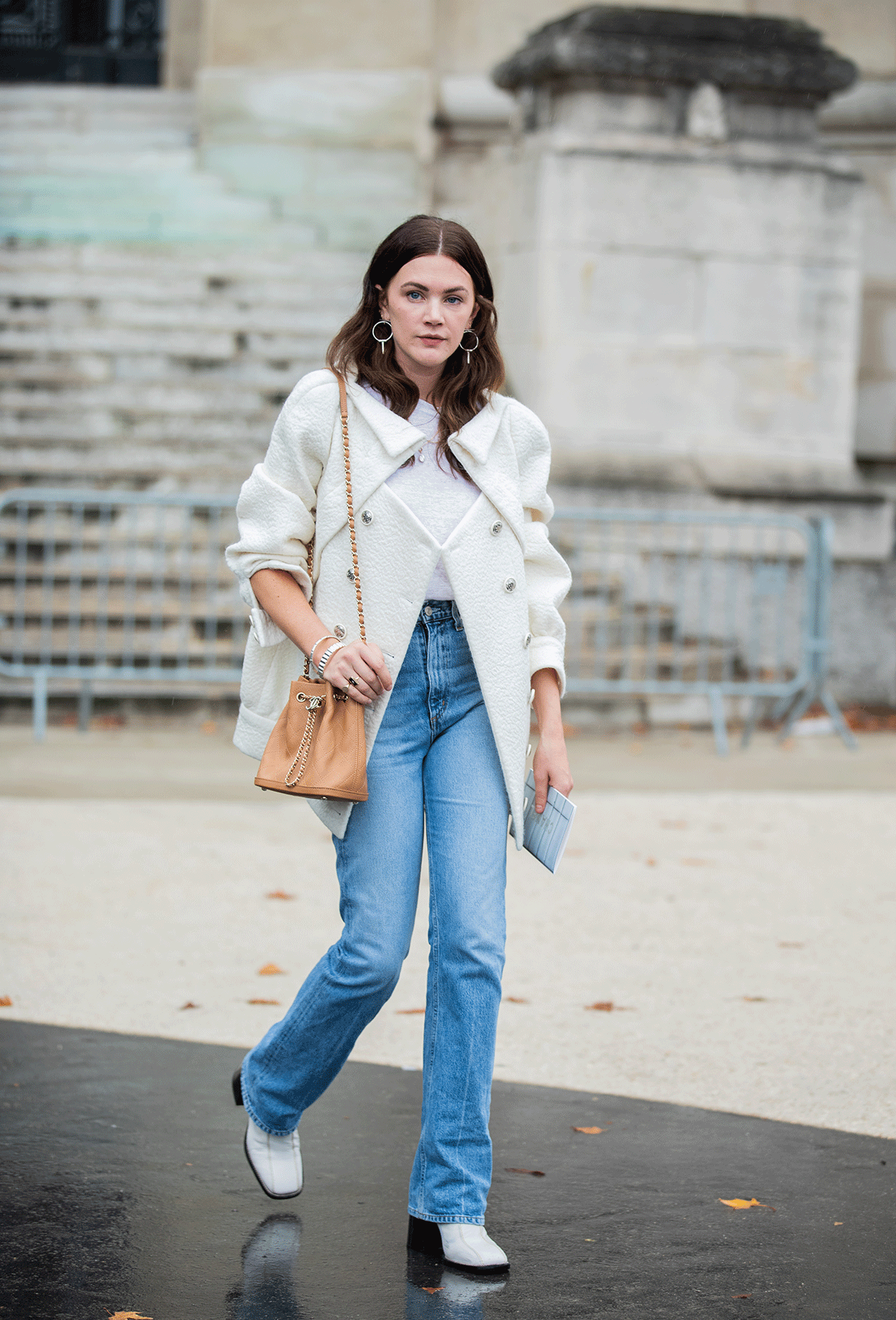 a photo showing how to style straight-leg jeans with a woman wearing a white jacket over a white top with jeans and white ankle boots