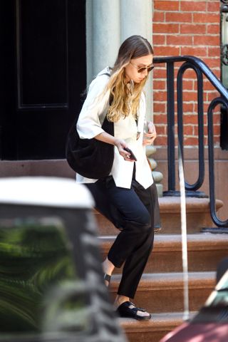 Ashley Olsen wearing white poplin shirt, leggings, and black Birkenstock sandals on New York stoop