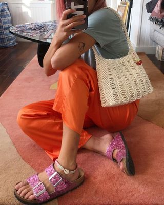 Michelle Li wearing orange pants, gray T-shirt with pink glitter Birkenstocks