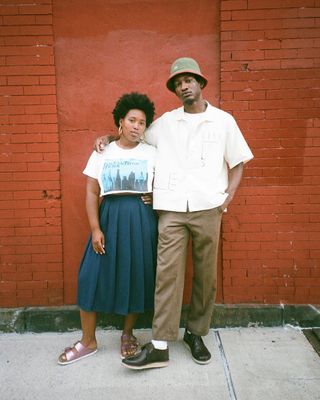 @meccajw wearing printed T-shirt, pleated midi skirt, and pink metallic Birkenstocks