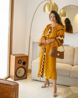 Bettina wears a printed maxi dress, a brown croc shoulder bag, and white heels.