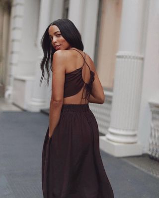 Woman looking over shoulder at camera on the streets of SoHo, New York, wearing brown maxi open back dress.