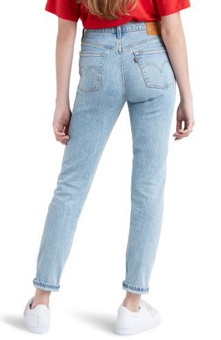 Woman with back to camera wearing Levi's 501 Skinny Jeans against white background