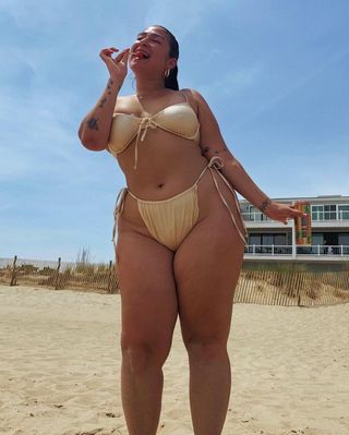 a photo of a curvy woman wearing a gold swimsuit