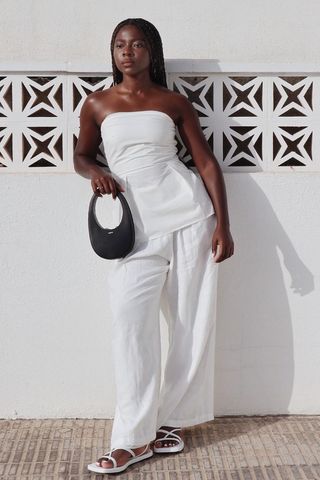 photo of a woman wearing white flat strappy sandals with all-white outfit, best sandals