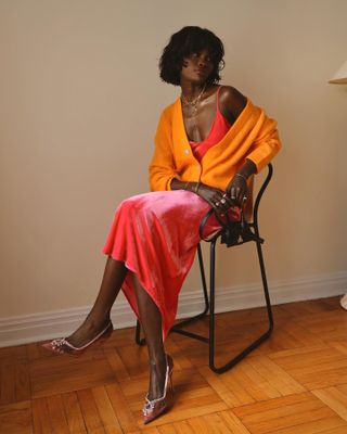 Woman sitting in a chair wearing a slip dress.