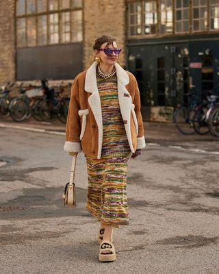 a woman's outfit with platform shearling sandals styled with a sweaterdress and shearling jacket