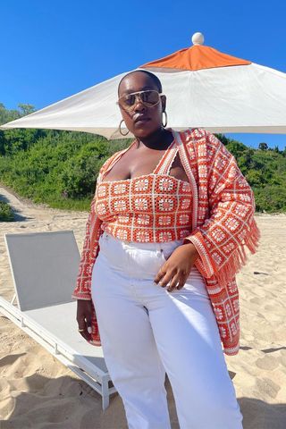 a photo of a woman's beach outfit with aviator sunglasses and hoop earrings and crochet set and white jeans