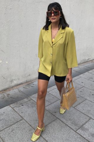 a photo of a woman's outfit with yellow mary jane shoes and biker shorts and an oversized button-down shirt
