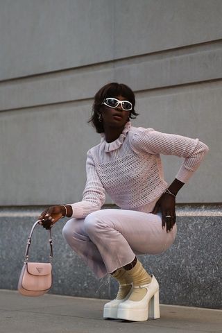 a photo of a woman's outfit with mary jane platforms, jeans, a pink top, and a sporty sunglasses