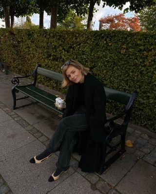 Woman sitting on park bench wearing all black and two-tone slingback heels.